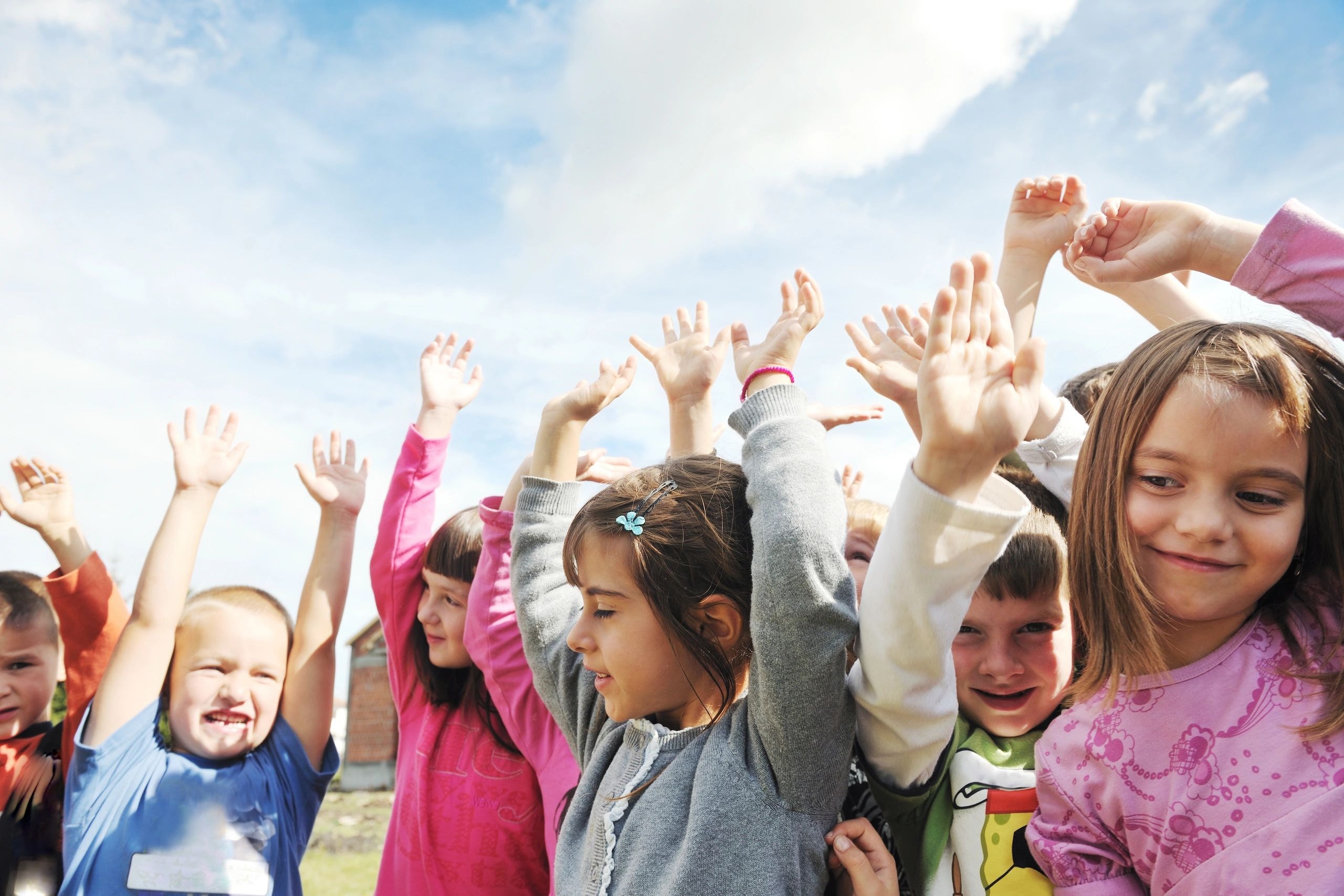 Group of children raising hands outdoors